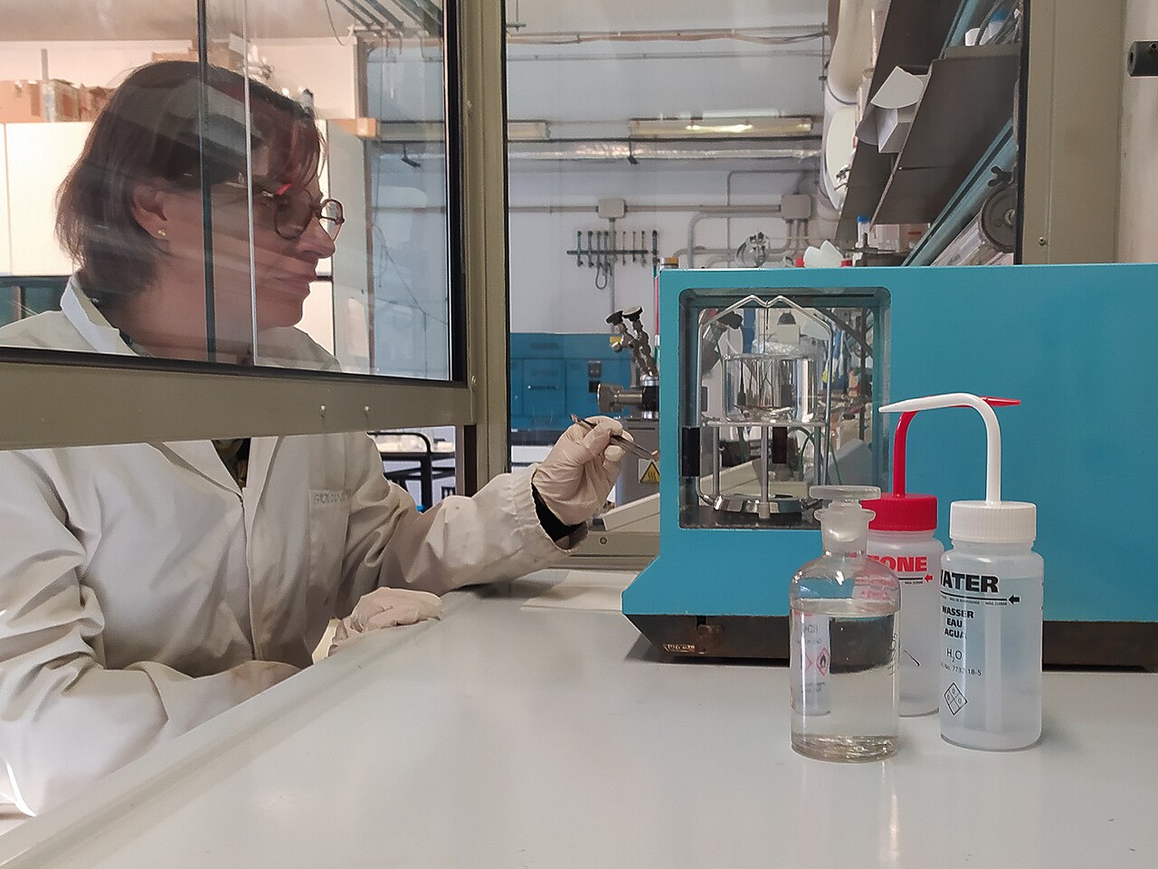 Científica midiendo la densidad de una muestra sólida con una balanza analítica y un kit de densidad